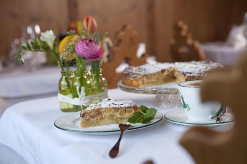a table with two plates of cake and a cup of coffee at Hotel Die Arlbergerin - Design & Tiroler Gemütlichkeit in Sankt Anton am Arlberg