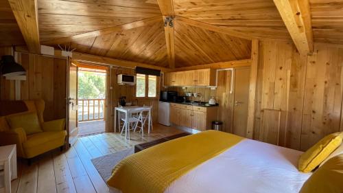 a bedroom with a large bed and a kitchen at Suspended Wooden House - Monte da Cortiça in Águas de Moura