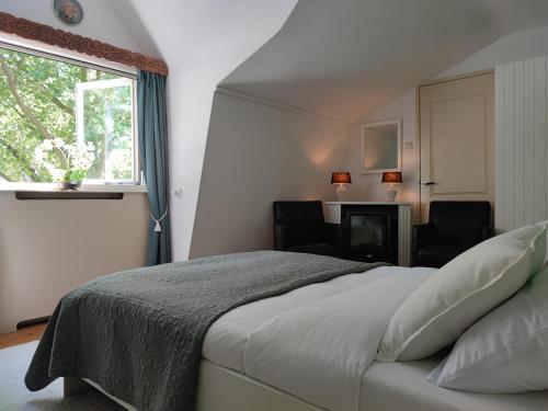 a bedroom with a bed with two chairs and a window at B&B Hotel Elselina in Schiedam