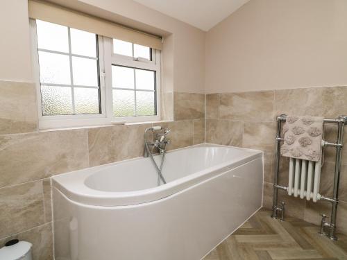 a white tub in a bathroom with a window at 2 Crosslands in York