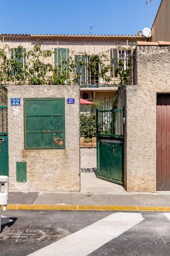 un bâtiment avec deux portes vertes sur son côté dans l'établissement SOLEIL EN VILLE - Coeur de ville, climatisatisé et au calme plein Sud à 300 m du Port Vieux, à La Ciotat