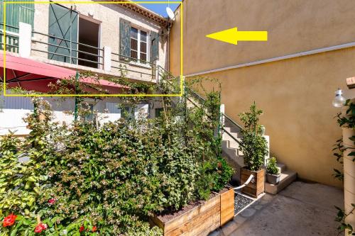 Un bâtiment avec une bande de plantes à côté d'un bâtiment dans l'établissement SOLEIL EN VILLE - Coeur de ville, climatisatisé et au calme plein Sud à 300 m du Port Vieux, à La Ciotat