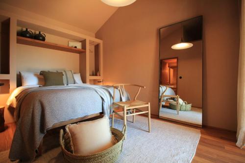 een slaapkamer met een bed, een stoel en een spiegel bij Vinha by NHôme in Ponte de Lima