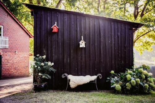 ein schwarzer Schuppen mit einer Bank davor in der Unterkunft Traumferienwohnung in der Lüneburger Heide in Soltau