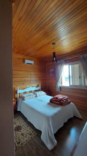 ein Schlafzimmer mit einem großen Bett und einer Holzdecke in der Unterkunft Refúgio do Lago in São Joaquim