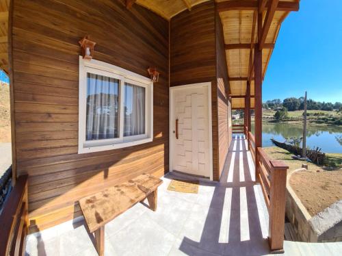 eine Holzhütte mit einer Tür und einer Bank in der Unterkunft Refúgio do Lago in São Joaquim