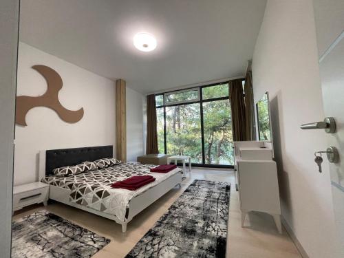 a bedroom with a bed and a large window at Greenside Apartment in Pristina