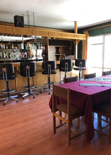 a room with a table and chairs and a bar at Hotel Las Vicuñas in Putre