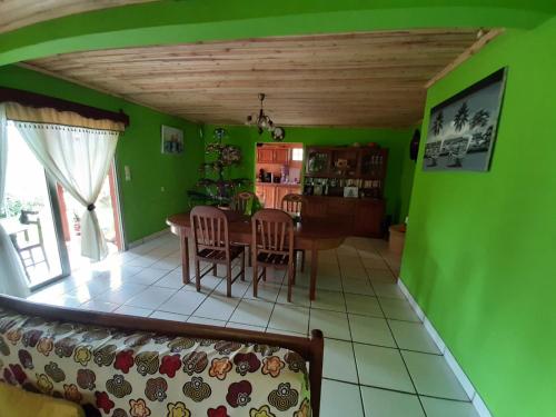 ein Wohnzimmer mit grünen Wänden sowie einem Tisch und Stühlen in der Unterkunft LA MARINA in Ambodifototra