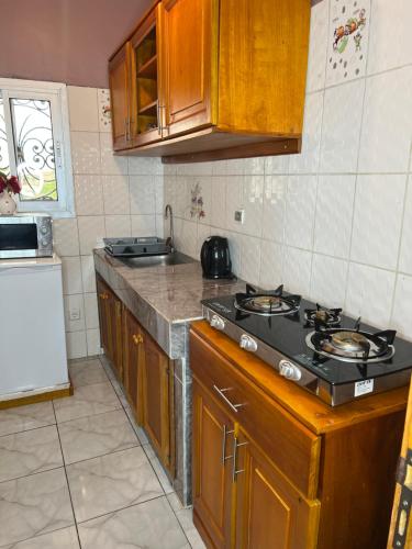 a kitchen with wooden cabinets and a stove top oven at Studio de haut standing, Bonamoussadi (Kotto) in Douala