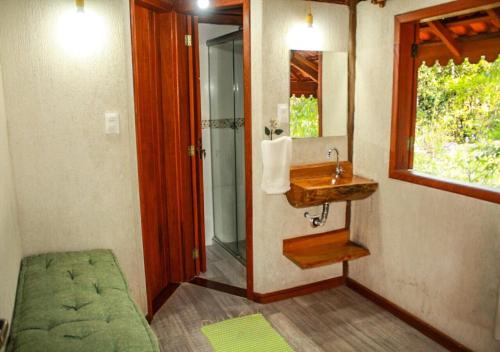 a bathroom with a sink and a shower and a mirror at Chale Canto dos Cristais in Visconde De Maua