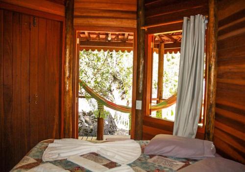 Schlafzimmer mit einem Bett vor einem Fenster in der Unterkunft Chale Canto dos Cristais in Visconde De Maua
