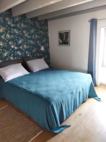 um quarto com uma cama com um cobertor azul em La ferme du vincent em Liergues