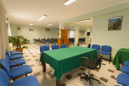 a conference room with a green table and blue chairs at Hotel Grillo in Nuoro