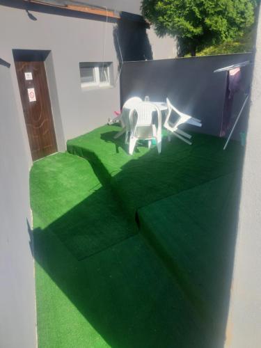 a fake lawn with a white table and chair on it at Ubytovanie v súkromí in Dolné Plachtince