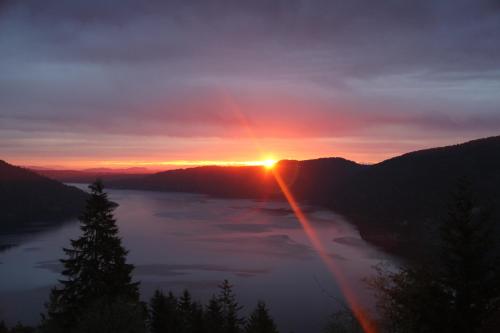 a sunset with the sun setting over a lake at Moon Water Lodge in Malahat