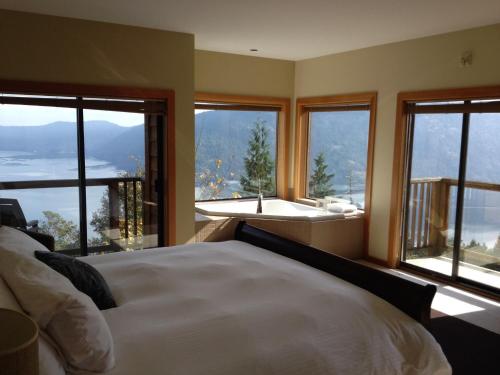 a bedroom with a bed and a bath tub and windows at Moon Water Lodge in Malahat
