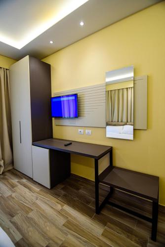 ein Zimmer mit einem Schreibtisch und einer Wand mit einem Fenster in der Unterkunft Hotel Orange in Dhërmi