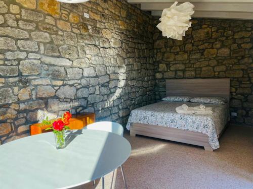 1 dormitorio con cama, mesa y pared de piedra en LA CASETTA SULLE NUVOLE PETRA, en Cammarata