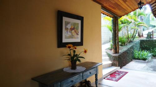 a room with a table with a vase of flowers at Pousada Cheiro da Terra in Cunha