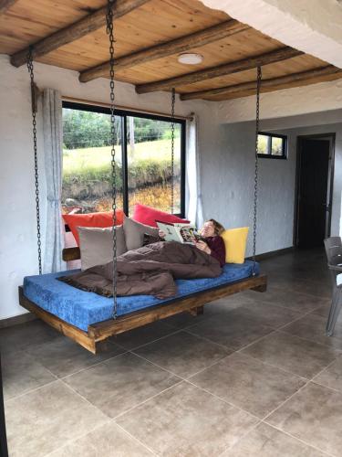 a man sleeping on a swing bed in a room at TOSCANA de Tomine in Guatavita