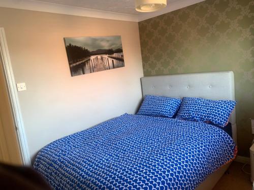 1 dormitorio con 1 cama con edredón azul en The Hamptons, en Shenley Lodge