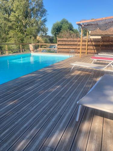une terrasse en bois à côté d'une piscine dans l'établissement GITE Sitio Nathalie et Jos, à Saint-Laurent-de-Carnols