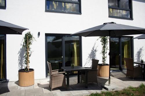 a table and chairs with an umbrella on a patio at Hotel HeideZeiten in Walsrode