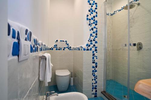 a bathroom with a toilet and a shower with blue tiles at ilTrucioloBBSuite in Anacapri