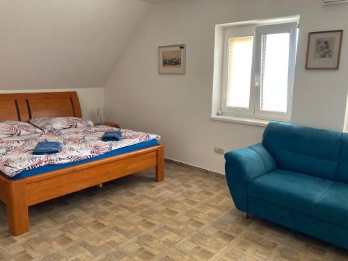 a bedroom with a bed and a blue couch at Apartmány s klimatizací - Penzion U Kudláčků Pouzdřany in Pouzdřany