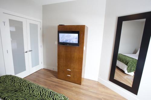 a room with a mirror and a television and a bed at Baymont by Wyndham Fort McMurray in Fort McMurray