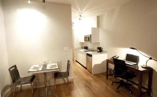 a small apartment with a desk and chairs and a kitchen at Baymont by Wyndham Fort McMurray in Fort McMurray