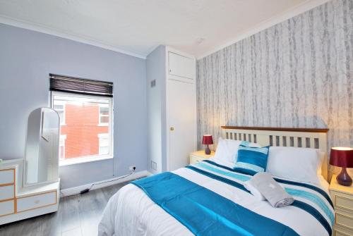 Dormitorio azul y blanco con cama y ventana en Crystal House 10min to Manchester City Centre ideal for work and leisure en Mánchester
