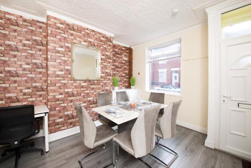 une salle à manger avec un mur en briques, une table et des chaises dans l'établissement Crystal House 10min to Manchester City Centre ideal for work and leisure, à Manchester
