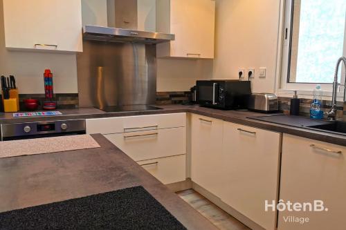 une cuisine avec des armoires blanches et un four à plaques de cuisson dans l'établissement CLIM Jolie maison de 60 m2 avec jardin, à Limoges