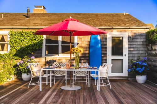 a table with chairs and a red umbrella on a deck at Sarah Jessica Parker’s Hamptons Hideaway in Amagansett