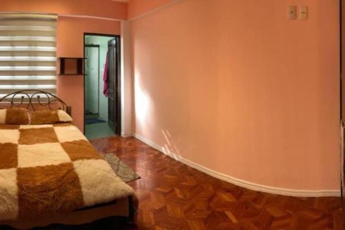 1 dormitorio con cama y pared de color naranja en Casa Jardín Recuérdame en Copacabana, en Copacabana