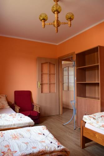 a bedroom with two beds and a red chair at Dom Muszelka in Lubiatowo