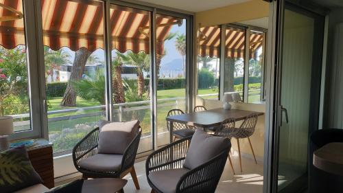 a screened porch with a table and chairs and windows at Garden and beach sea view apartment Cannes in Cannes