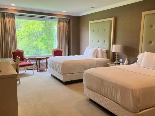 um quarto de hotel com duas camas e uma janela em Rocky River Inn em New Milford