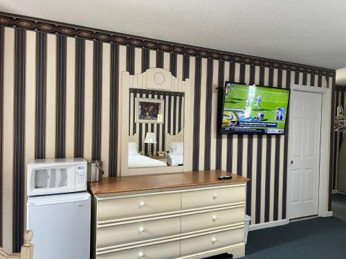 Rocky River Inn في New Milford: غرفة مع ميكروويف وخزانة مع تلفزيون