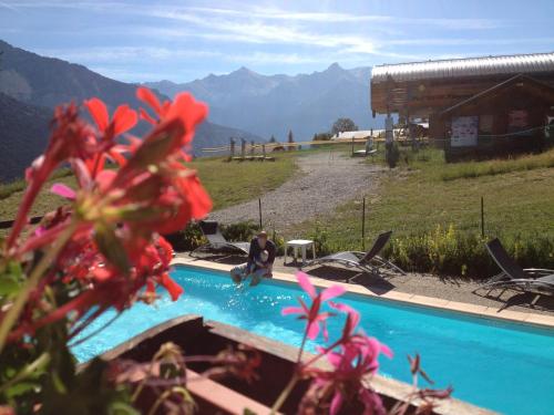 un homme assis à côté d'une piscine avec des montagnes en arrière-plan dans l'établissement Mountainhotel Saint Roch, à Puy-Saint-Vincent