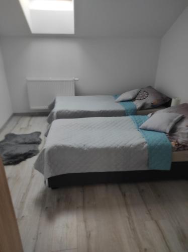 een slaapkamer met 2 bedden en een houten vloer bij Nocleg na Poziomkowej in Kościerzyna
