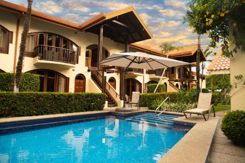 uma casa com piscina e guarda-sol em Apartotel Girasol em Jacó