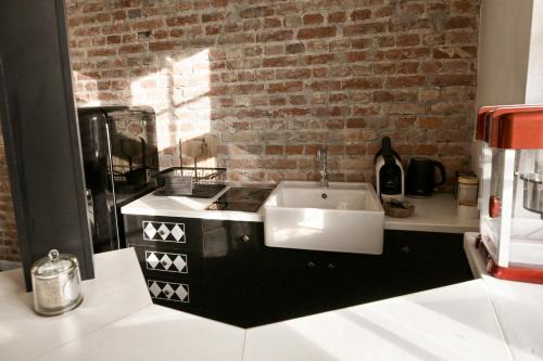 une cuisine avec un évier blanc et un mur en briques dans l'établissement Dream Factory Apartment, à Varsovie