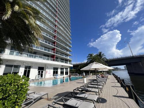 a swimming pool with lounge chairs next to a building at 23rd floor Luxury & Spacious BeachWalk Resort Apartment with Amazing View in Hallandale Beach