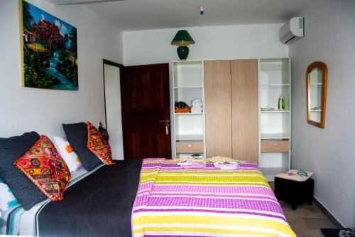 um quarto com uma cama com um cobertor colorido em Villa Prunepassion em Le Moule