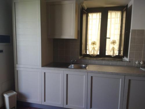 d'une cuisine avec des placards blancs, un évier et une fenêtre. dans l'établissement Casa Cecilia, à Gallico Marina