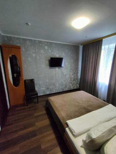 a bedroom with a bed and a tv on the wall at Hotel Almaz in Poltava