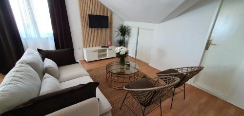 uma sala de estar com um sofá, cadeiras e uma mesa em Apartmani Masline em Jasenice